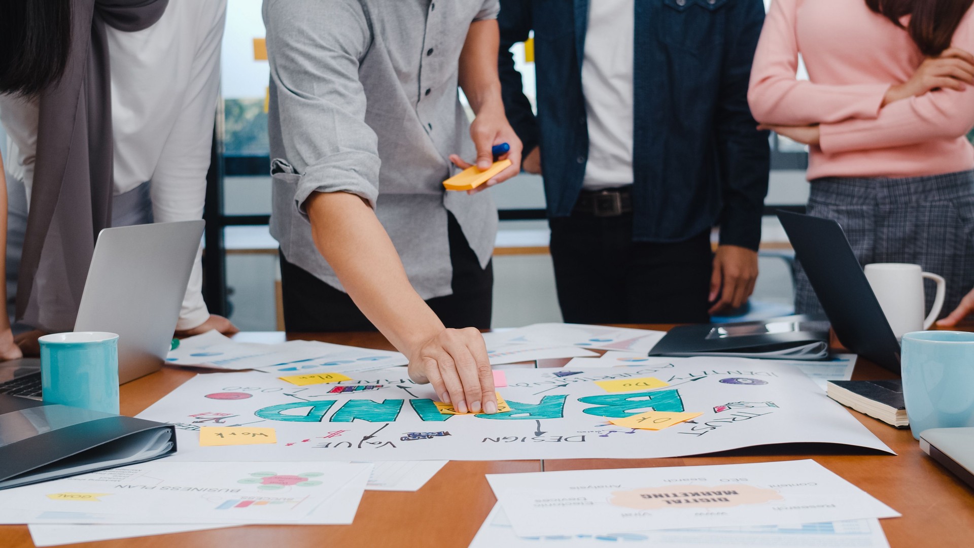 Happy young Asian businesspeople meeting brainstorming ideas about new paperwork project colleagues working together planning success strategy enjoy teamwork in small modern office.